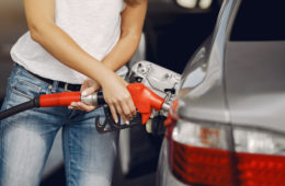 Woman on a gas station. Lady in a white t-shirt. Woman near the car.